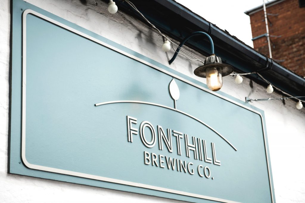 Fonhill Brewing Co.'s logo cut in wood and painted with their brand's blue outside the brewery